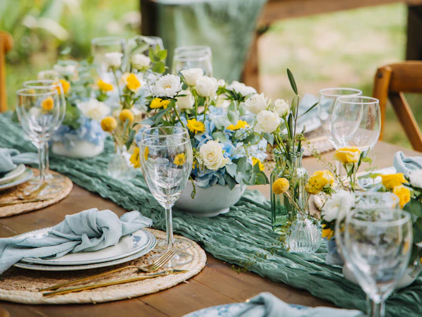 Mesa de banquete puesta con platos, servilletas, copas y flores